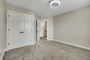Unfurnished bedroom featuring carpet flooring, baseboards, and a closet
