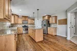 Kitchen with stainless steel appliances, a sink, dark wood finished floors, a center island, and recessed lighting