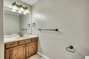 Bathroom with vanity, toilet, and baseboards
