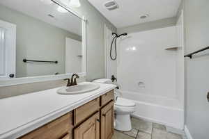Full bath featuring toilet, vanity, tub / shower combination, and stone finish flooring