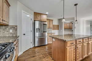 Kitchen with appliances with stainless steel finishes, dark wood-style flooring, stone countertops, decorative backsplash, and recessed lighting