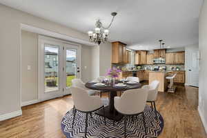 Dining room with wood finished floors, a chandelier, baseboards, and recessed lighting