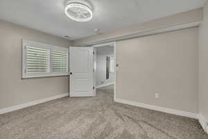 Unfurnished bedroom featuring carpet floors, baseboards, and a textured ceiling