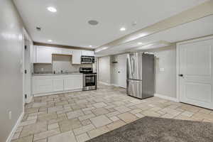 Kitchen with appliances with stainless steel finishes, baseboards, white cabinetry, and recessed lighting