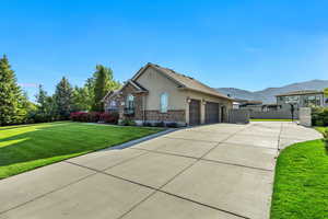 View of front of property with an attached garage, concrete driveway, stucco siding, a mountain view, and brick siding