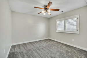 Spare room with carpet flooring, a ceiling fan, and baseboards