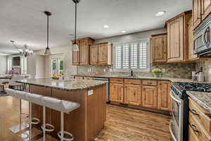 Kitchen featuring appliances with stainless steel finishes, a kitchen breakfast bar, a sink, decorative backsplash, and recessed lighting