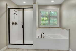 Full bathroom featuring a shower stall, a bath, and tile patterned floors