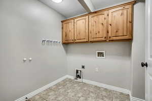 Laundry room featuring washer hookup, cabinet space, light tile patterned floors, hookup for an electric dryer, and baseboards