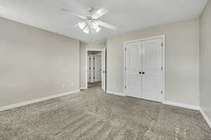 Unfurnished bedroom with carpet flooring, baseboards, a closet, and a ceiling fan