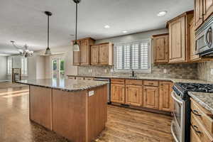 Kitchen with appliances with stainless steel finishes, a sink, backsplash, wood finished floors, and recessed lighting