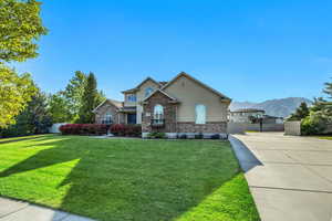 View of front of home featuring stucco siding, a gate, a mountain view, concrete driveway, and stone siding