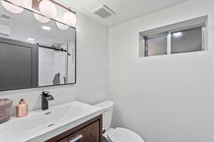 Full bath featuring toilet, vanity, tiled shower, a textured ceiling, and recessed lighting