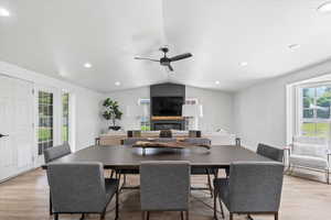 Dining area with lofted ceiling, a large fireplace, ceiling fan, light wood-style flooring, and recessed lighting