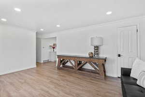 Living area with crown molding, light wood finished floors, recessed lighting, and baseboards