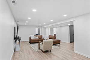 Living room with baseboards, recessed lighting, and light wood-style flooring