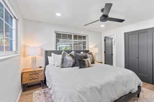Bedroom featuring light wood-style floors, multiple windows, baseboards, and recessed lighting