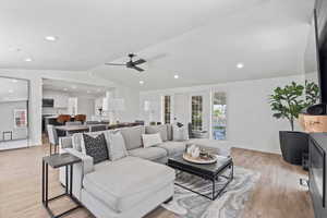 Living room with light wood-style floors, lofted ceiling, ceiling fan, recessed lighting, and baseboards