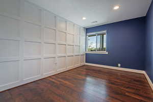 Empty room featuring baseboards, recessed lighting, dark wood-style floors, and a textured ceiling