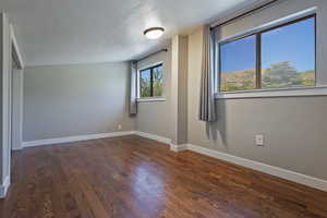 Unfurnished room featuring a textured ceiling, wood finished floors, and baseboards