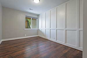 Spare room featuring dark wood-type flooring and baseboards