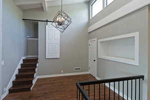 Stairway featuring a barn door, wood finished floors, a chandelier, baseboards, and beamed ceiling