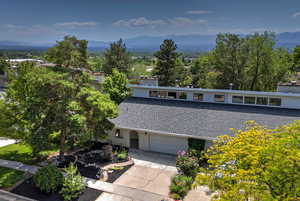 View of front facade with a mountain view, a garage, concrete driveway, brick siding, and a chimney
