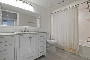 Full bath with toilet, vanity, shower / bath combo with shower curtain, and tile patterned floors