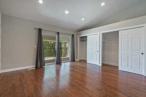 Unfurnished bedroom with two closets, lofted ceiling, recessed lighting, dark wood-type flooring, and baseboards