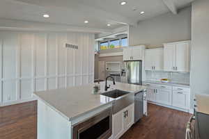 Kitchen with a sink, stainless steel appliances, decorative backsplash, beamed ceiling, and dark wood-type flooring