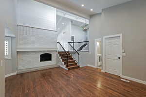 Foyer with stairway, a brick fireplace, a chandelier, a high ceiling, and baseboards