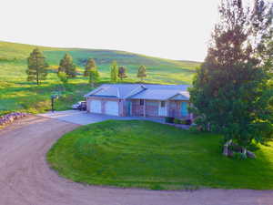 View of front of home with a garage, driveway, a front lawn, metal roof, and covered porch