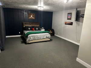 Bedroom with carpet floors, baseboards, and a textured ceiling