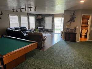 Playroom with a wood stove, a textured ceiling, billiards, carpet flooring, and wood finished floors