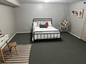 Bedroom featuring carpet flooring, a textured ceiling, and baseboards