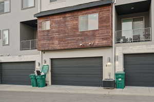 Back of property with central AC unit, stucco siding, a garage, and a balcony
