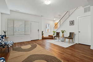 Foyer with wood finished floors, baseboards, and stairway