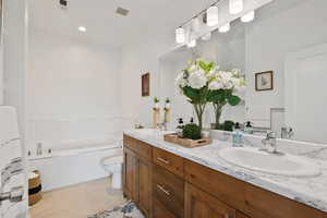 Bathroom featuring a garden tub, double vanity, toilet, and tile patterned floors