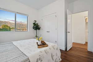 Bedroom with dark wood-type flooring, a closet, and baseboards