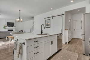 Kitchen with a sink, stainless steel appliances, a barn door, white cabinets, and open floor plan