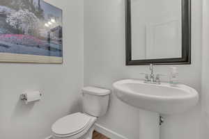 Bathroom featuring baseboards, toilet, and wood finished floors