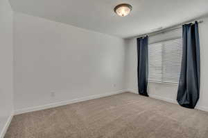 Spare room with carpet flooring, baseboards, and a textured ceiling