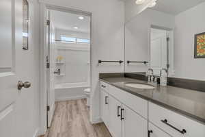 Bathroom with vanity, toilet, wood finished floors, and washtub / shower combination