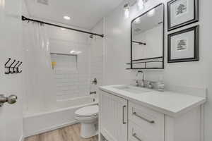Full bathroom with vanity, shower / tub combo with curtain, wood finished floors, and toilet