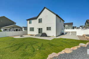 Rear view of house with a patio area, entry steps, stucco siding, and roof mounted solar panels