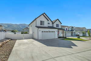 View of front of home featuring board and batten siding, an attached garage, a gate, concrete driveway, and a mountain view