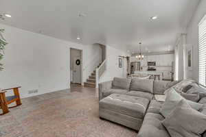 Living area with stairway, a chandelier, light wood finished floors, healthy amount of natural light, and recessed lighting