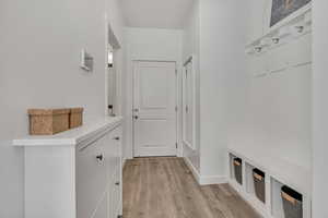 Mudroom with light wood finished floors and baseboards