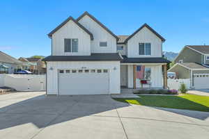 Modern farmhouse with board and batten siding, a gate, driveway, and a garage
