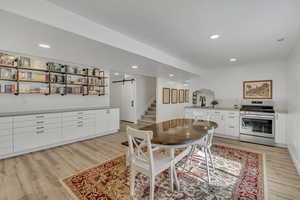 Dining room with a barn door, light wood-style floors, stairs, recessed lighting, and arched walkways